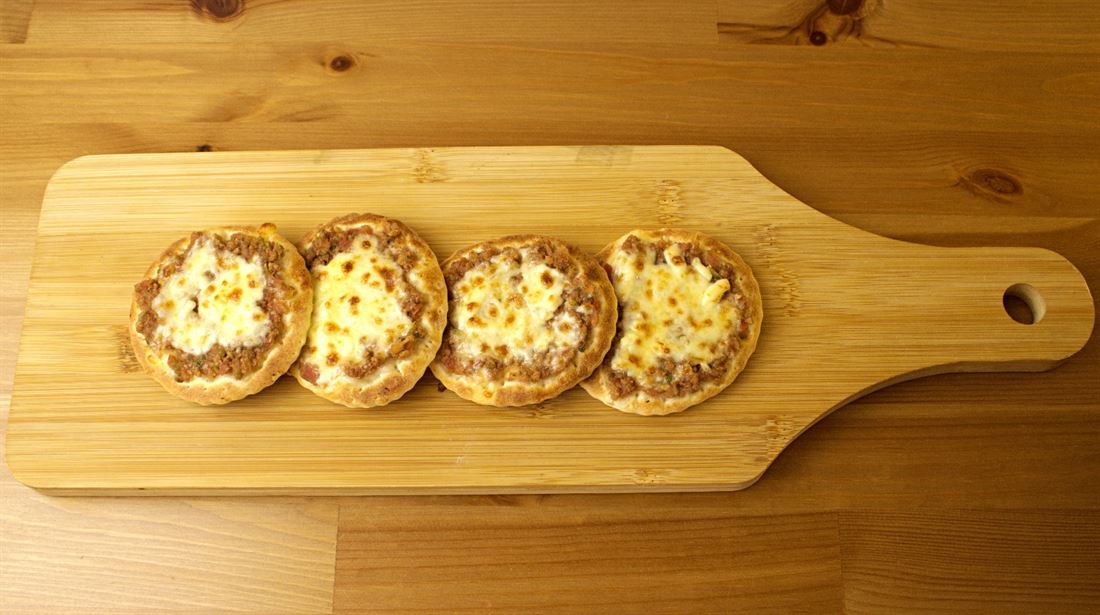 Mini meat and cheese pies on a wooden board