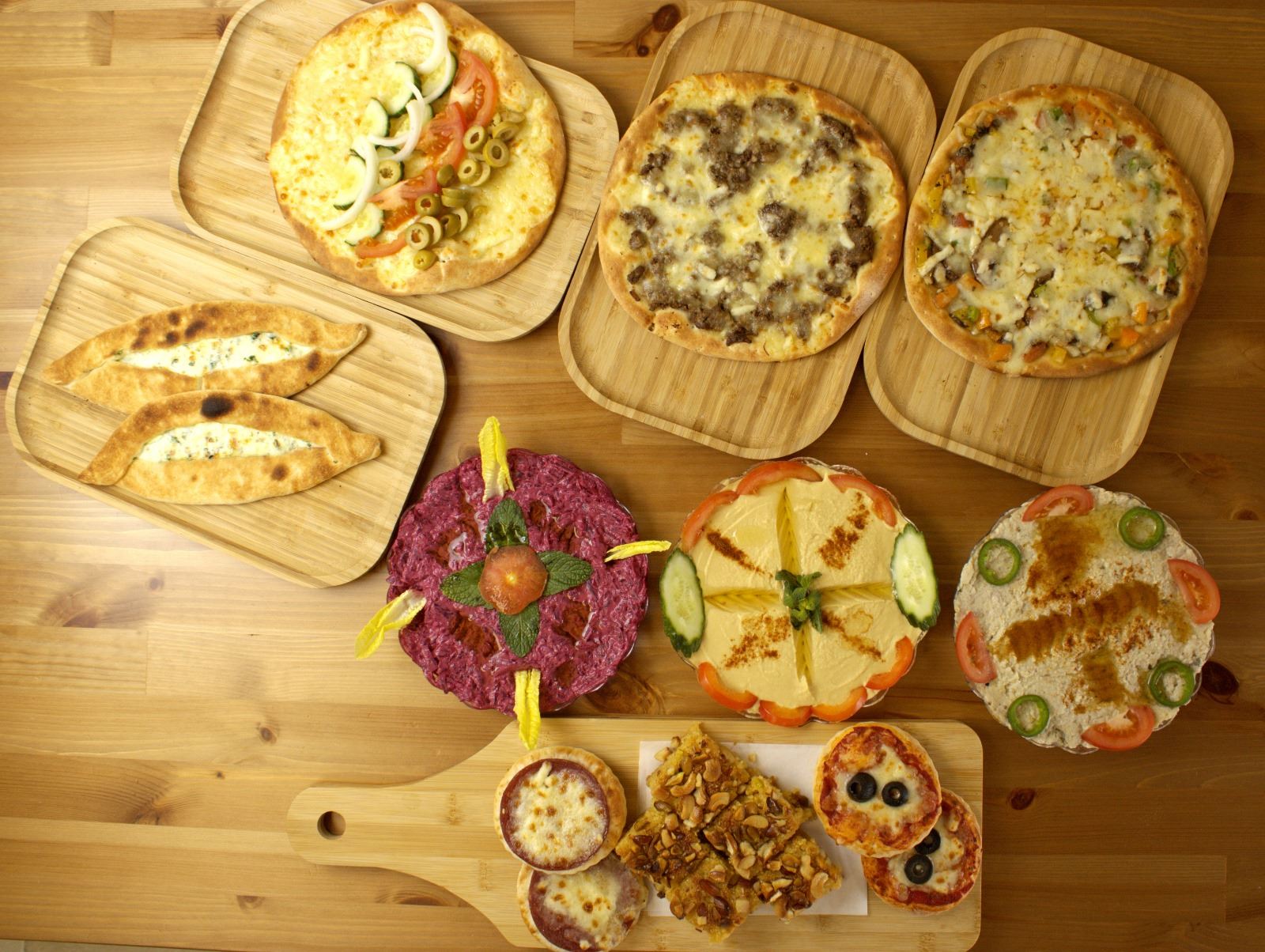 A spread of pies, dips and mini pizzas on wooden boards